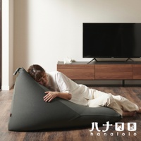 灰色針織布懶骨頭沙發，呈現三角形，一位女性斜躺其中，沙發置於木地板上，背景為電視與木製櫃。