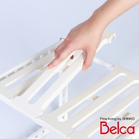 白色伸縮槽下單層站立收納架，由塑膠材質製成，有兩層置物平台，平台上有長條形鏤空設計，方便排水。手部正在調整其中一層的長度。