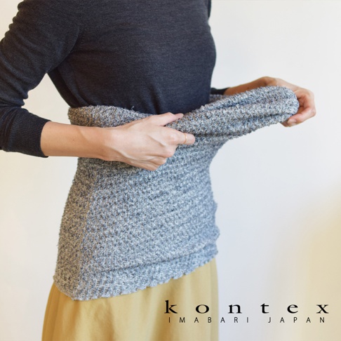 人物正在穿著灰色條紋的毛織長裙，裙子從腰部圍起，品牌KONTEX IMABARI JAPAN的標誌在右下方。