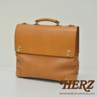 焦糖色皮革兩用波士頓包，設有頂部提把、金色旋轉鎖扣及包角加固縫線。