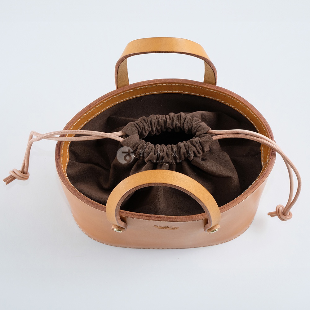 職人手作皮革束口手提包，淺棕色皮革，內襯為深棕色絨布，束口處有淺棕色細繩，搭配兩個弧形提把。