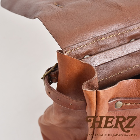 復古棕色水洗皮革郵差包，展示包蓋、皮革內襯、金屬扣環及縫線細節。