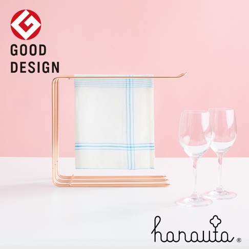 玫瑰金不鏽鋼三桿抹布架，掛有一條白色藍格紋抹布，旁邊擺放兩只透明高腳杯。