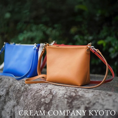 京都職人手作隨身側背包，皮革材質，展現棕色、藍色和紅色三種顏色。包身設計簡約，肩帶細長，適合日常攜帶。