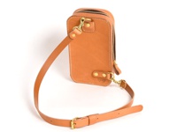 職人手作皮革兩用直立型斜背包，呈現自然棕褐色，材質為真皮。包款設有拉鍊開口，並配有可拆卸的皮革斜背帶，背帶上有金屬扣環，整體風格簡約實用。