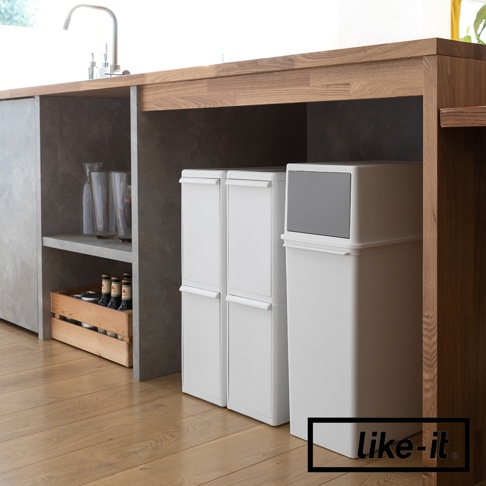 兩個白色長版可疊垃圾桶並排，右側有一個較大的白色垃圾桶，頂部配有灰色蓋子，均擺放在木製檯面下方。