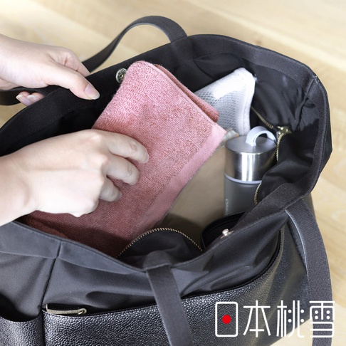 日本桃雪飯店運動毛巾，黑色托特包裡放入粉紅色毛巾和保溫瓶