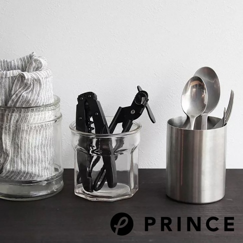 玻璃罐中裝有一條白色與黑色條紋的布巾，旁邊的透明玻璃罐內有黑色旋轉開罐器，右側則有一個銀色金屬罐，裡面插著湯匙和叉子。