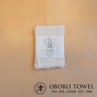 一條米白色三層紗純棉戶外掛脖毛巾，帶有手繪圖案包裝紙，標有日文文字。