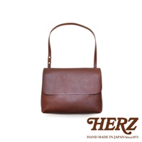 職人手作皮革經典郵差包 CK-4 M，採用厚實的皮革材質，呈現自然紋理，為棕褐色調。包款設計簡約，翻蓋式開口，搭配可調節長度的細肩帶，適合斜背或單肩背。