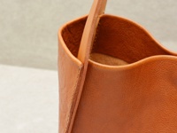 職人手作皮革Organ方形托特包 (G-68) M，特寫展示其溫潤的焦糖棕色皮革，細膩的紋理與精緻車縫線，展現材質與工藝的質感。