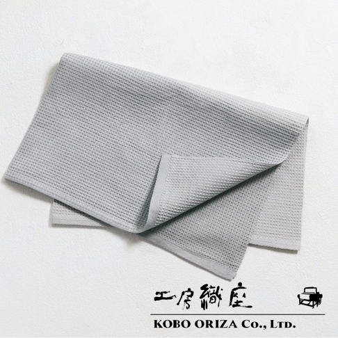 灰色的棉麻混紡拭巾，表面有鬆餅紋理，一角疊起，展現細緻的織紋。