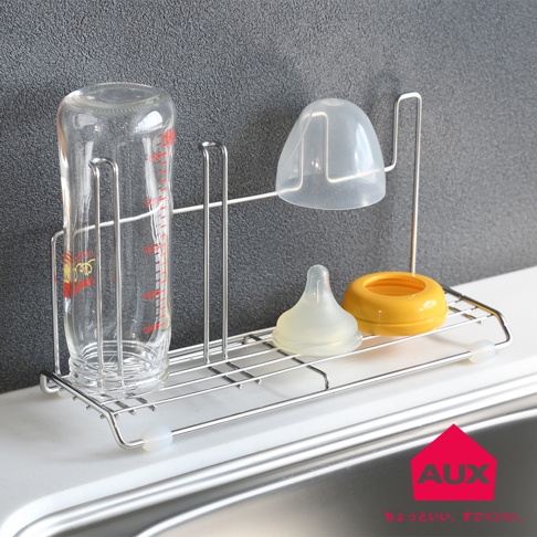 不鏽鋼製奶瓶瀝水架，架上放置一個透明玻璃奶瓶、一個透明奶嘴蓋、一個白色矽膠奶嘴和一個黃色奶瓶蓋。