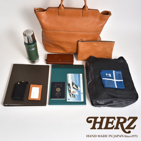 職人手作皮革大容量兩用托特包 T-8，展示有棕褐色皮革托特包、同色系化妝包、錢包，以及綠色文件夾、日本護照、筆、綠色保溫瓶與黑色網狀收納袋，整體陳列。