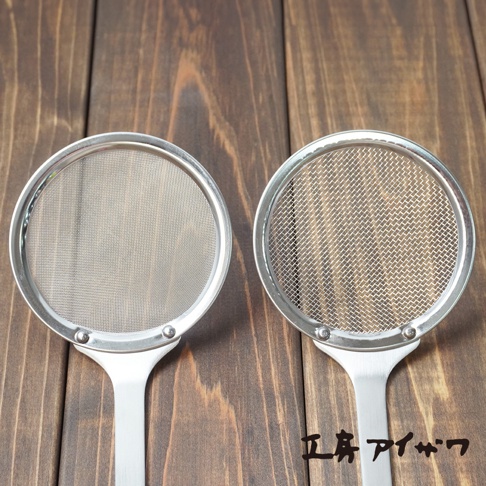 兩件不鏽鋼材質的撈油勺，均帶有圓形細網篩，銀色金屬手柄，置於木紋背景上。