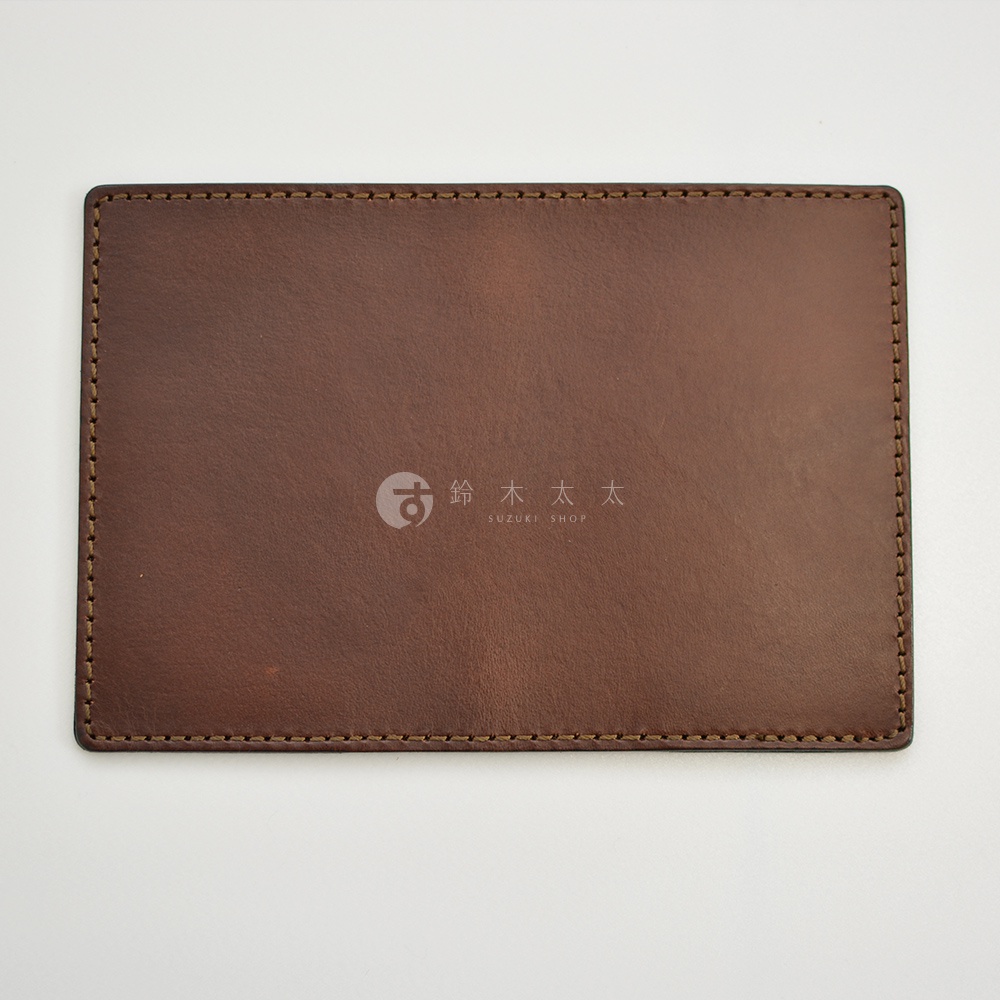 職人手作皮革經典護照套，採用深棕色牛皮製作，邊緣以同色系車縫線精緻縫合，中央印有品牌標誌。