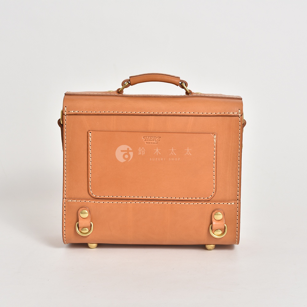 職人手作的學院風迷你後背包，使用淺棕色皮革製成，有頂部提把、前方收納袋及金屬扣環，風格簡約復古。