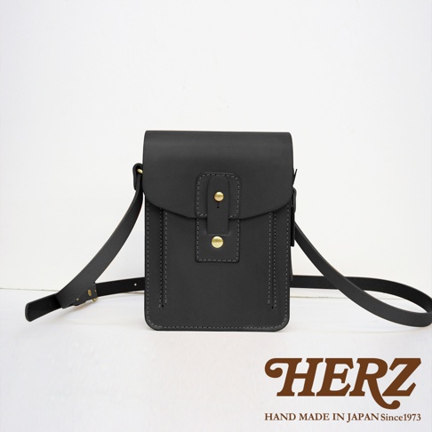 職人手作皮革散步包，黑色，附斜挎肩帶，包身有雙重縫線設計，正面有翻蓋與兩顆黃銅色金屬釦。