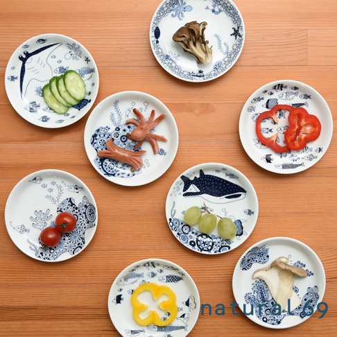 多個白色陶瓷小碟子，分別裝有小黃瓜片、香腸、紅椒塊、葡萄、番茄、黃椒圈及菇類。碟子上印有藍色海洋生物圖案，如魚、章魚、鯨鯊及珊瑚。