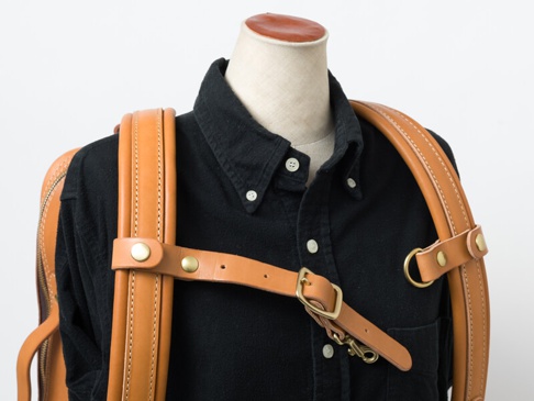 職人手作皮革背包用減壓胸前扣帶，採用天然棕色皮革製成，配有黃銅色金屬扣環及調節帶，設計簡潔實用。