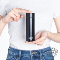 一個人雙手拿著一個黑色的圓柱形保溫杯，杯身上印有白色邊框的「POKETLE」標誌。