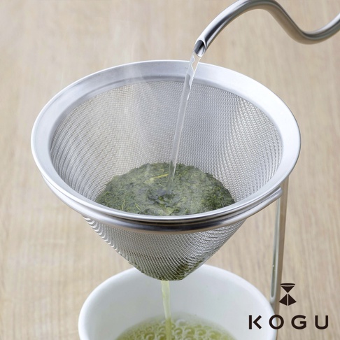 日製18-8不鏽鋼濾茶器，網眼細緻，附有金屬支架，正在過濾茶葉，下方為茶杯。