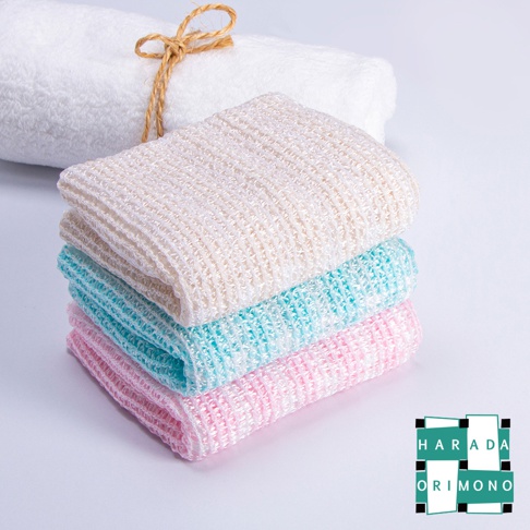 一條白色毛巾，其上疊放著三條泡泡洗澡巾，分別為米白色、淺藍色和粉紅色，材質為網狀織物。