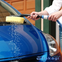 黃色長方形洗車海綿，連接黑色手柄與藍白色水管接頭，水從海綿滴落，用於清潔藍色汽車。