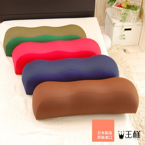 四個不同顏色（棕色、藍色、紅色、綠色）的王樣膝下枕，呈現波浪形狀，擺放在白色床單上。