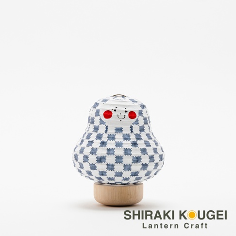 達摩不倒翁造型提燈，白色紙質燈身印有藍色細格紋，臉部有兩顆紅色圓點和微笑表情，底部為木製圓形座。