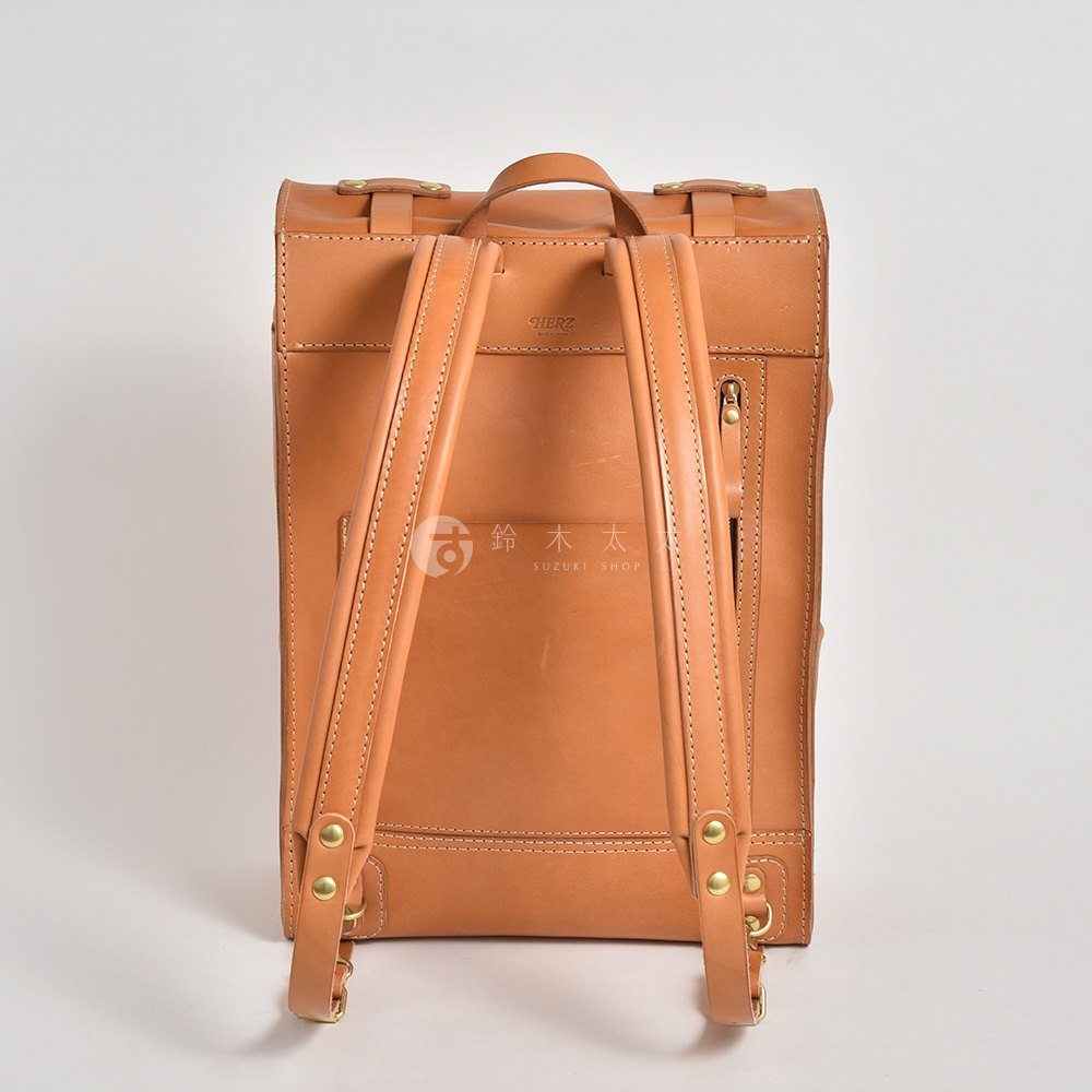 職人手作皮革後背包，呈現自然的棕褐色，材質為皮革，設計簡約大方，適合露營登山等戶外活動。