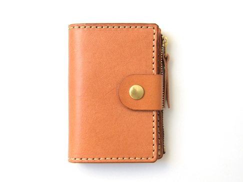 職人手作的棕色皮革零錢鑰匙包，設有金色拉鍊和按扣，縫線整齊，設計簡約。