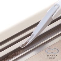 白色塑膠製成的縫隙清潔刷，末端呈扁平狀，正在清理窗溝中的塵土。