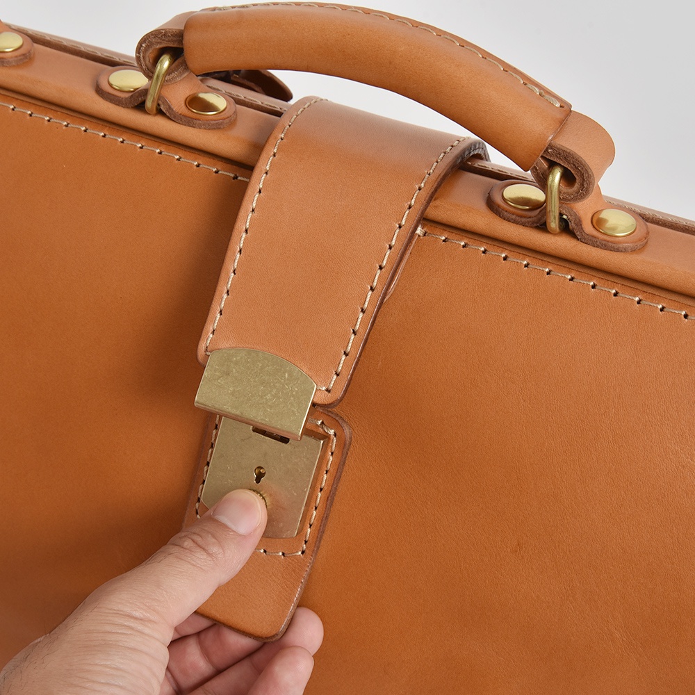 棕色皮革公事包特寫，展示了手提把、鎖扣和縫線細節。