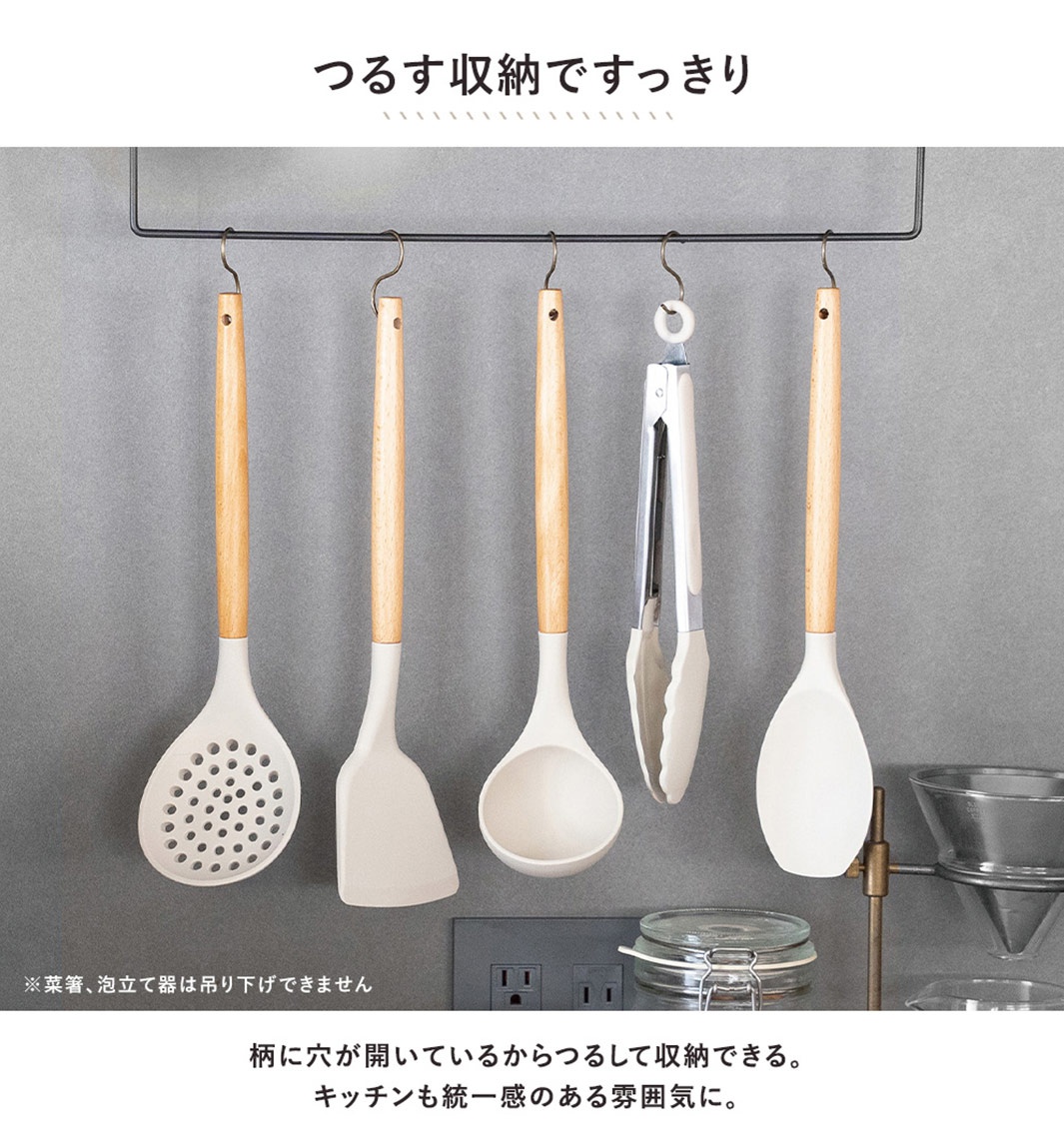 一套白色矽膠廚房用具，包含漏勺、鍋鏟、湯勺、夾子等，皆配有木質手柄，並懸掛於收納架上，背景為灰色牆面。