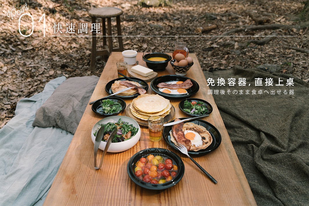 木質桌面擺放著豐盛的戶外早餐，包含煎鍋、鬆餅、培根煎蛋、沙拉、番茄以及飲品。