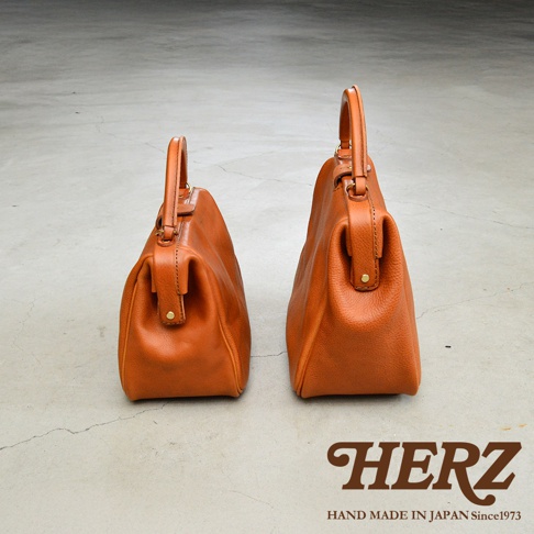 兩款不同尺寸的職人手作皮革Organ方形口金托特包，皆為棕褐色，圓潤的包身配備提把與金屬釦。