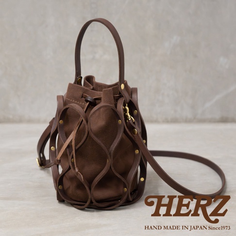 日本HERZ職人手作皮革Organ編織水桶包，深棕色皮革與絨面內裡，附有可調整背帶，品牌標誌和製造資訊置於右下角