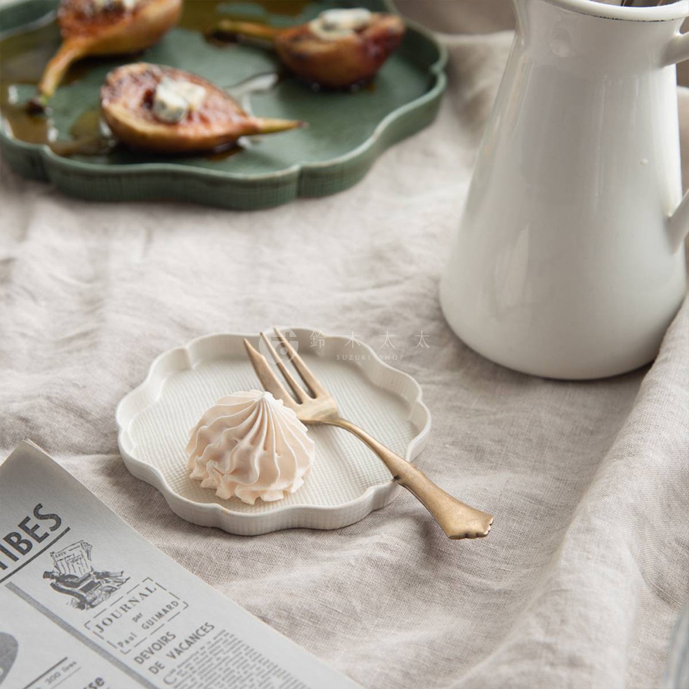 美濃燒白色花型淺盤，帶有細緻紋理，盤上放著一個淡粉色蛋白霜餅和一支金色叉子。