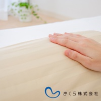 手輕撫著淺米色條紋的圓柱形夾腿枕，枕套材質觸感柔順。