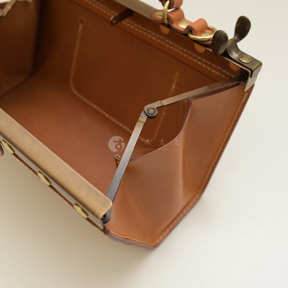 職人手作皮革復古口金兩用手提包，呈現經典的棕色皮革，配以黃銅色金屬口金及鎖扣，包身結構穩固，內部設計簡潔，適合日常攜帶。