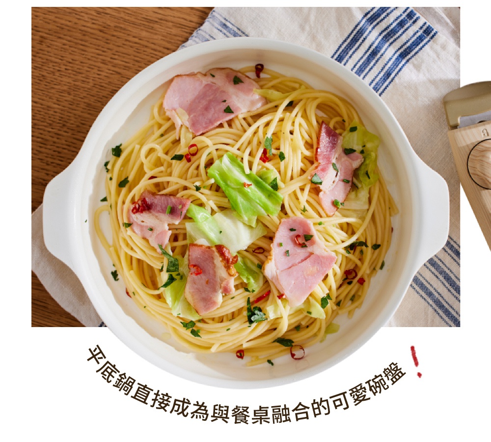 白色的陶瓷平底鍋盛著義大利麵，配料有培根、高麗菜和辣椒，鍋子有兩個把手，旁邊有木柄的鍋蓋。
