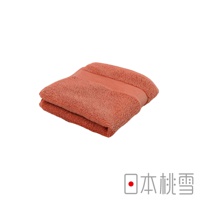 一條珊瑚色今治匹馬棉方巾，質地柔軟，對折後呈現立體感，邊緣有壓紋設計。