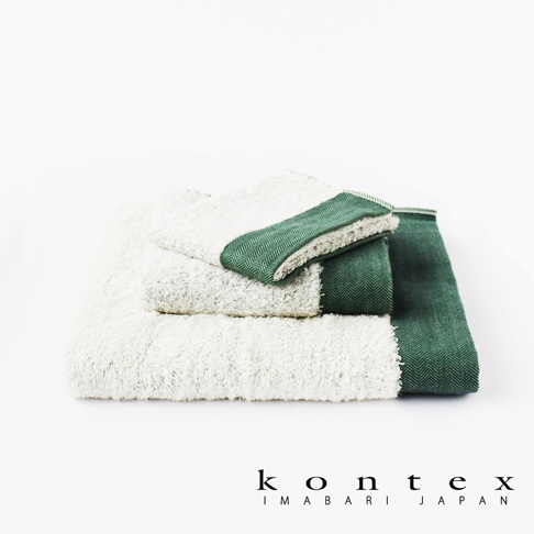 疊放的HERRINGBONE斜紋圖案今治長纖有機棉浴巾，主體為米白色，兩條浴巾的邊緣飾有深綠色斜紋織帶。