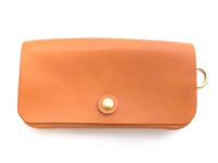 橘色皮革長夾，設有金色按扣及側邊金色 D 型環，適合旅行收納。