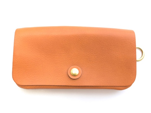 橘色皮革長夾，設有金色按扣及側邊金色 D 型環，適合旅行收納。