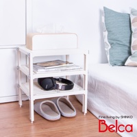 白色塑膠迷你三層收納架，架上置有紙巾盒、書籍和黑色耳機，下方擺放著一雙灰色條紋拖鞋。