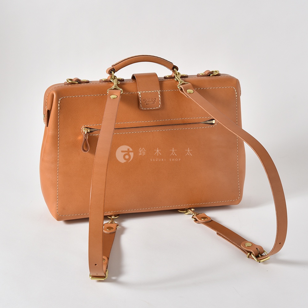 職人手作皮革軟式杜勒斯三用背包，淺棕色，設有拉鍊暗袋、手提把及可拆卸調整的背包帶，搭配金屬扣環。