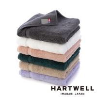 一疊六色今治毛巾，包含深灰、純白、淺粉、墨綠、米褐與淡紫，毛巾表面呈現細緻絨毛質感。