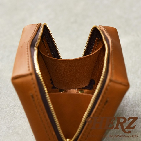 一咖棕色皮質的箱型收納包，拉鍊部分開啟，露出內部皮革隔層。